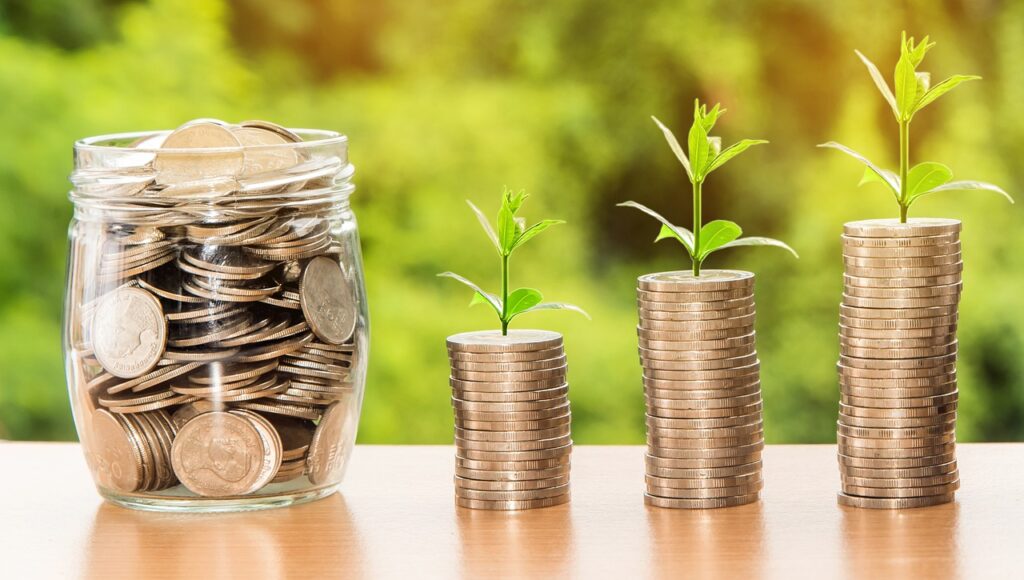 Coins stacked with small plants growing, symbolizing financial growth and investment success.