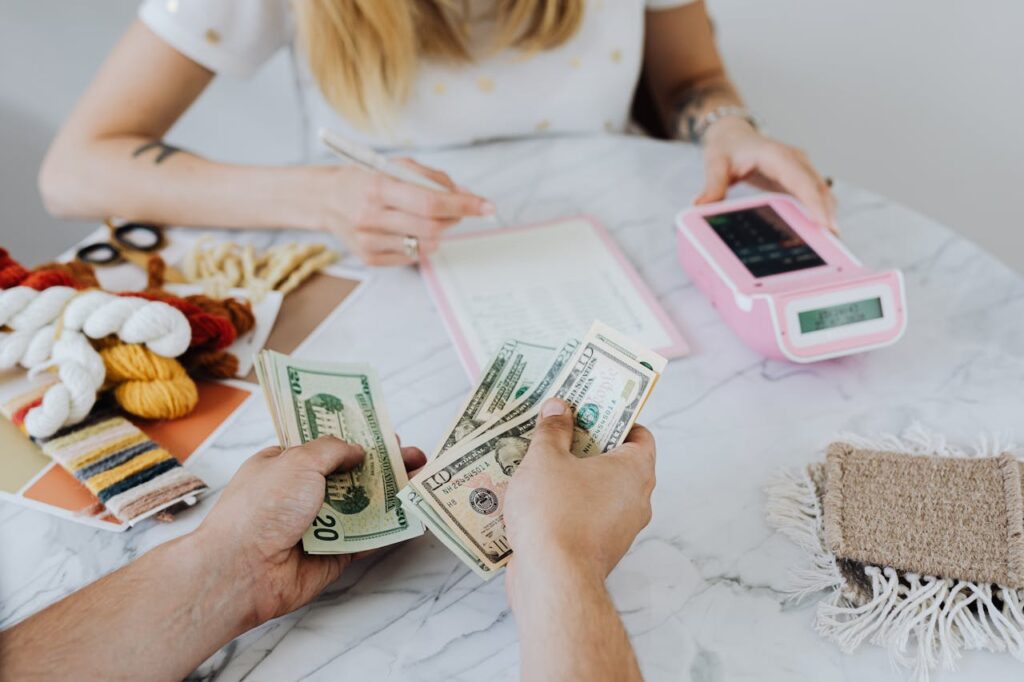 Person counting cash at a table with a payment terminal, symbolizing budgeting and financial planning