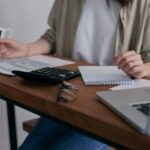 A lady with a pen in hand writing down her personal finance strategies as a beginner.