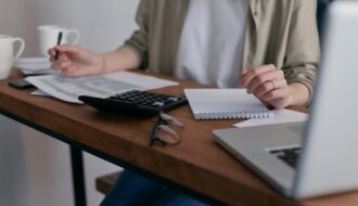 A lady with a pen in hand writing down her personal finance strategies as a beginner.