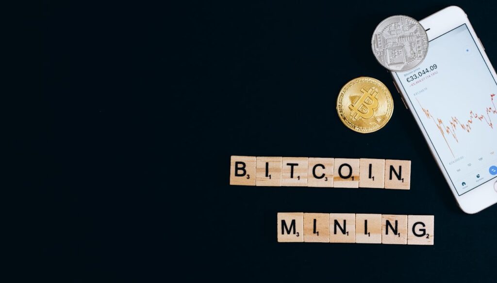 Bitcoin mining concept with cryptocurrency coins, mobile price chart, and scrabble tiles spelling 'Bitcoin Mining'.