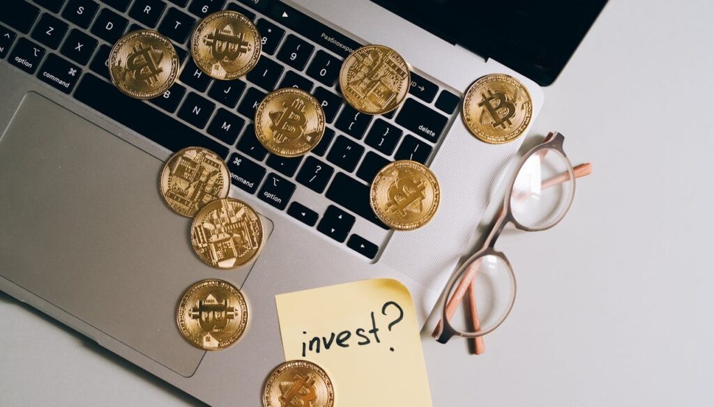 Cryptocurrency investment concept with Bitcoin coins on a laptop and 'invest?' note